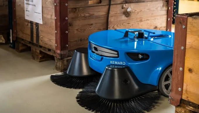 KEMARO K900 sweeping between crates in a warehouse